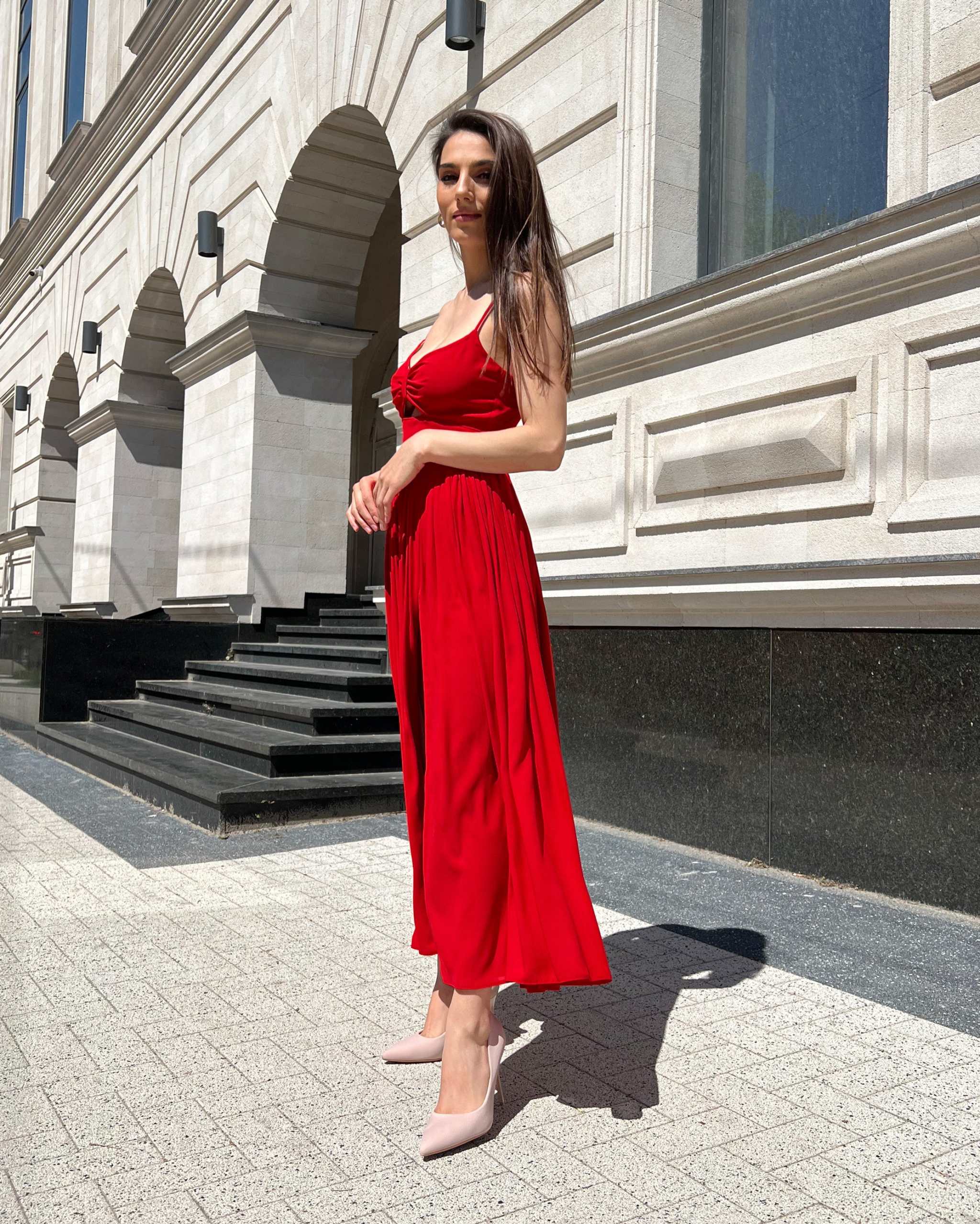 Rochie rosie midi elegantă cu bretele subțiri și decupaj frontal.