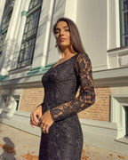 Rochie neagra din dantelă cu mâneci lungi și decolteu mic, purtată afară.