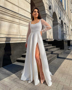 Rochie de mireasa albă lungă din satin elegantă cu șliț și mâneci transparente.