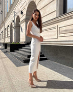 Rochie cocktail albă elegantă fără mâneci cu slit pe picior și croială ajustată.