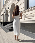 Rochie cocktail albă elegantă fără mâneci, ajustată, cu slit pe picior, vedere spate.