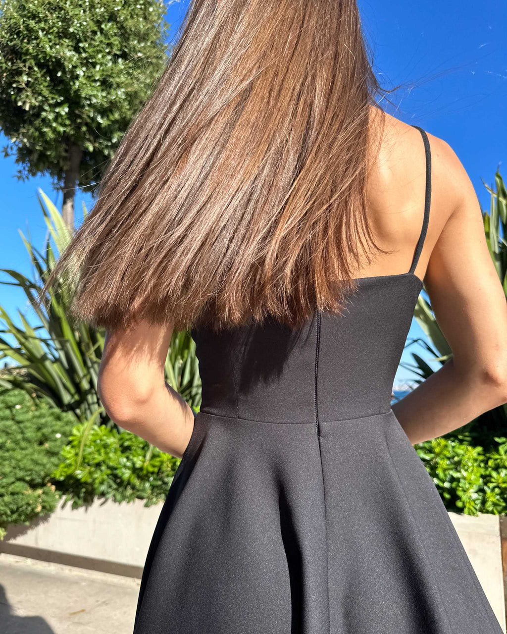 Rochie neagra elegantă scurtă cu bretele și fustă evazată.