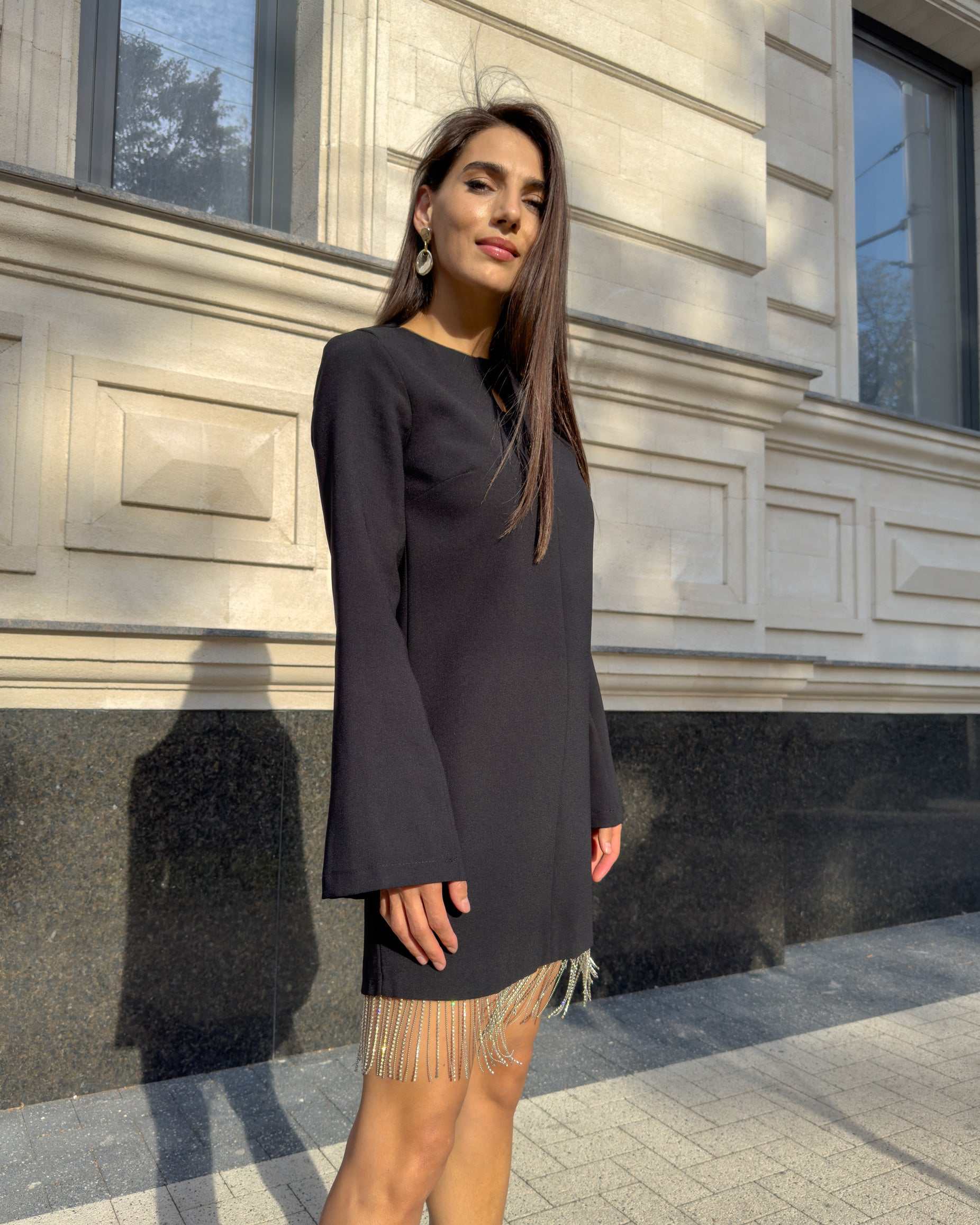 Rochie neagra scurta cu franjuri din cristale, maneci lungi, detalii decorative, sistem de inchidere cu fermoar.