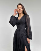 Rochie lunga neagră cu mâneci lungi elegante și șliț, corset evidențiat.