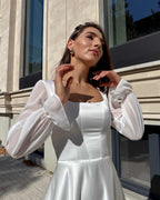 Rochie de mireasa lungă cu corset, decolteu elegant și mâneci semitransparente, ideală pentru nunți.