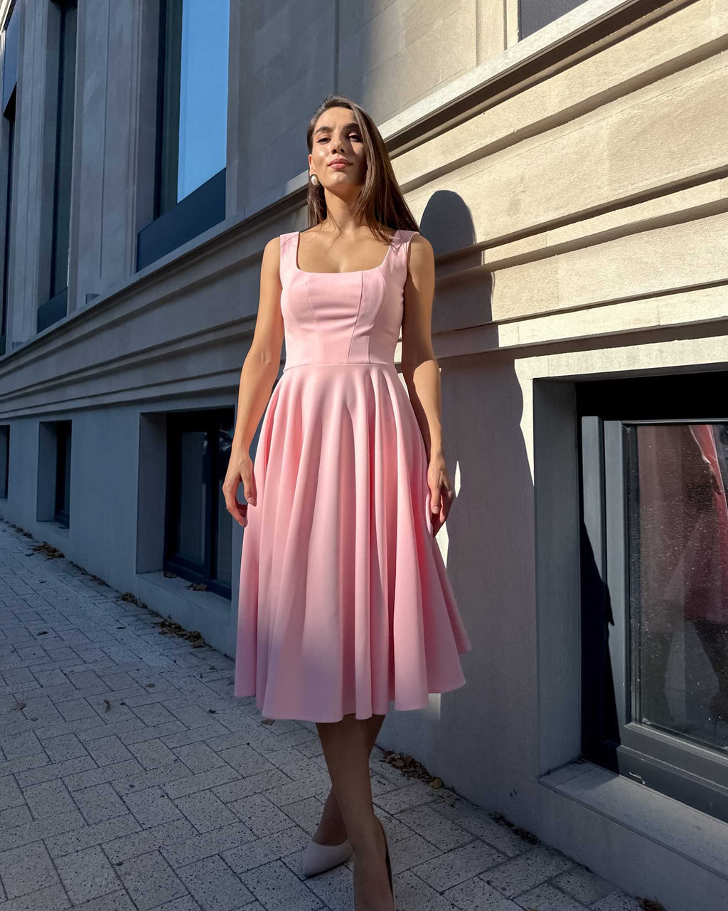 Rochie roz eleganta roz midi cu decolteu în lumina soarelui.