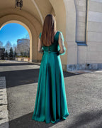 Rochie lunga verde smarald din satin cu mâneci transparente și spate cu nasturi, eleganță sofisticată pentru evenimente speciale.