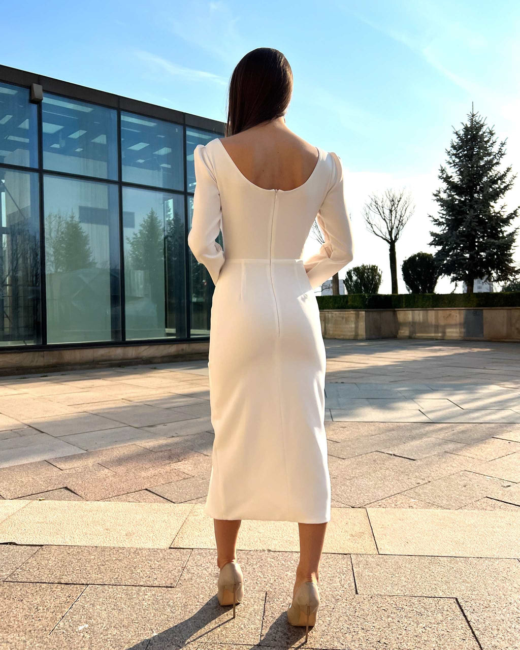 Rochie albă elegantă cu mâneci lungi și slit, vedere din spate, potrivită pentru evenimente speciale.