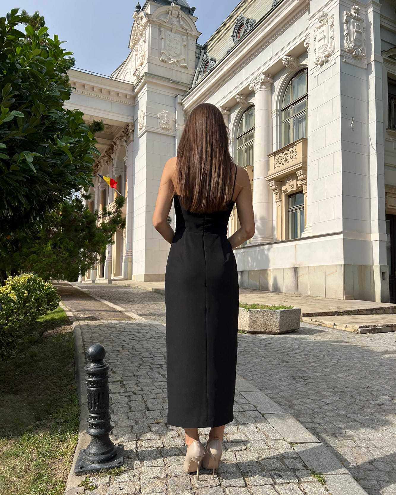 Rochie eleganta neagră de ocazie din crep elastic cu slit, vedere din spate, croială ajustată pe corp.