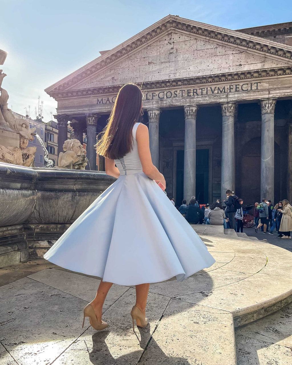 Rochie eleganta midi bleu, fără mâneci, cu șliț și decolteu, din satin regal în fața unui monument.