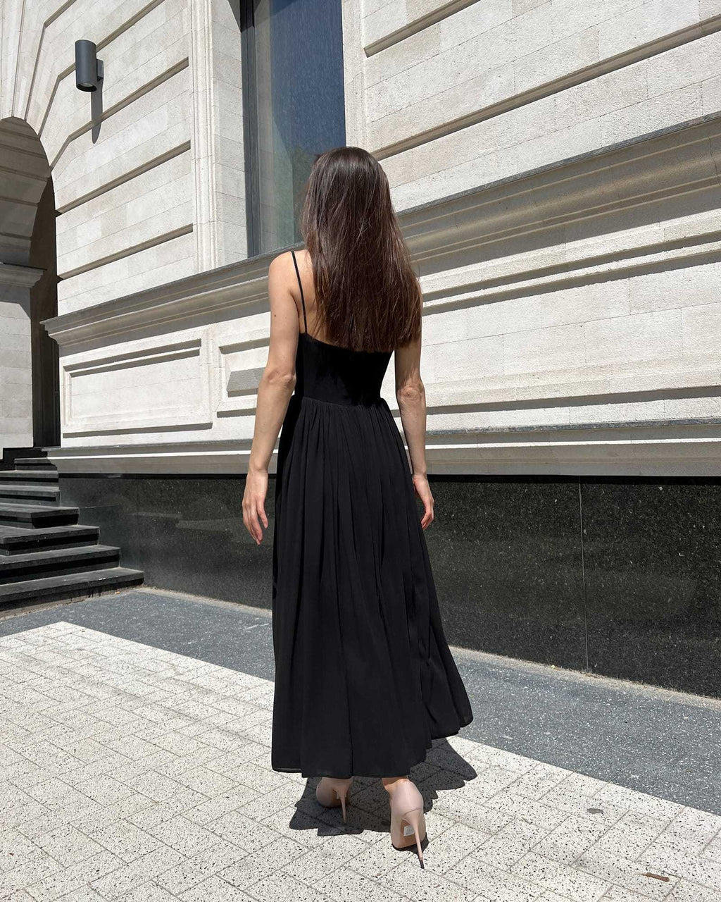 Rochie neagra cu bretele si slit pe picior, vazuta din spate, model in picioare.